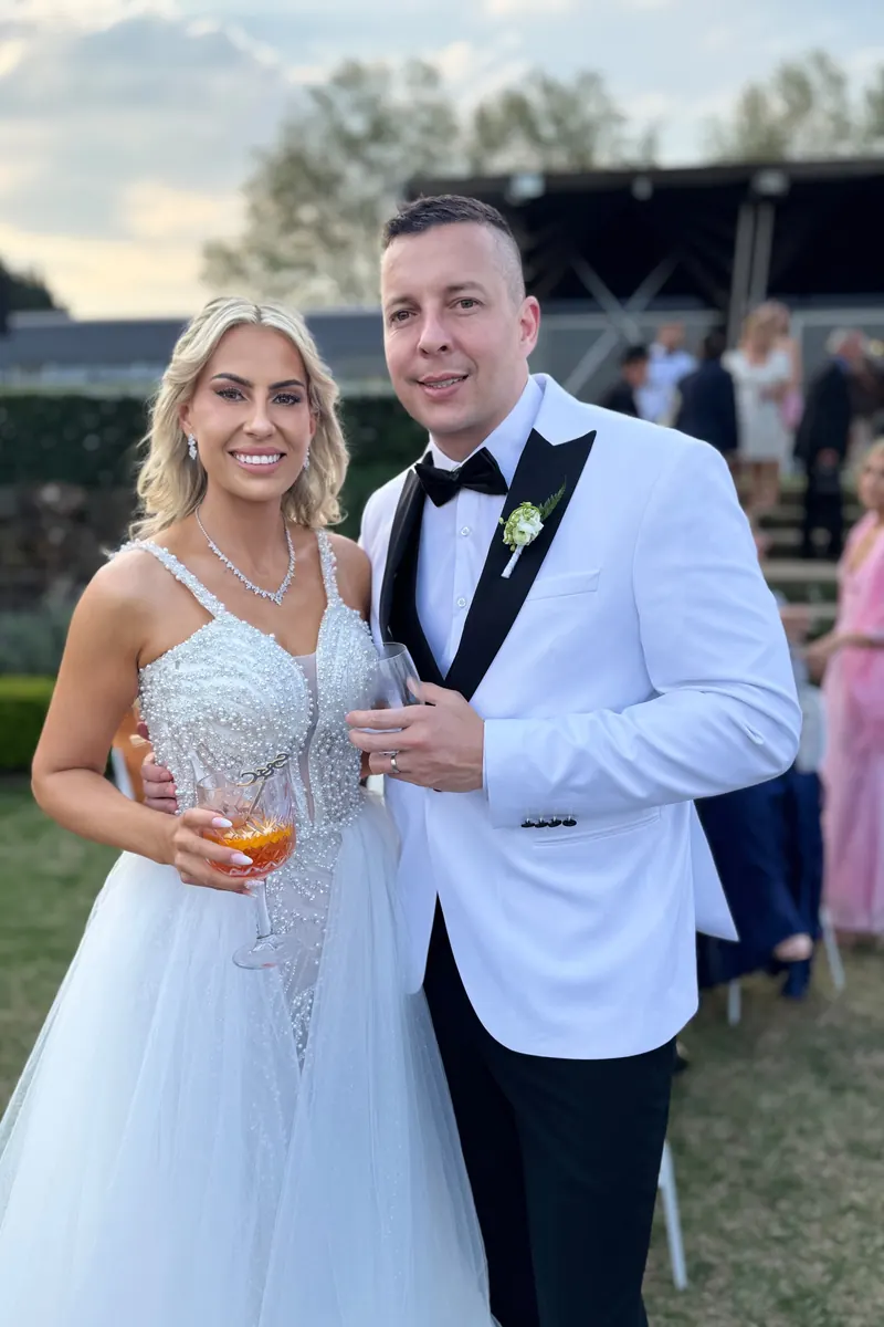 A bride and groom holding drinks at an outdoor KZN wedding, raw phone photo