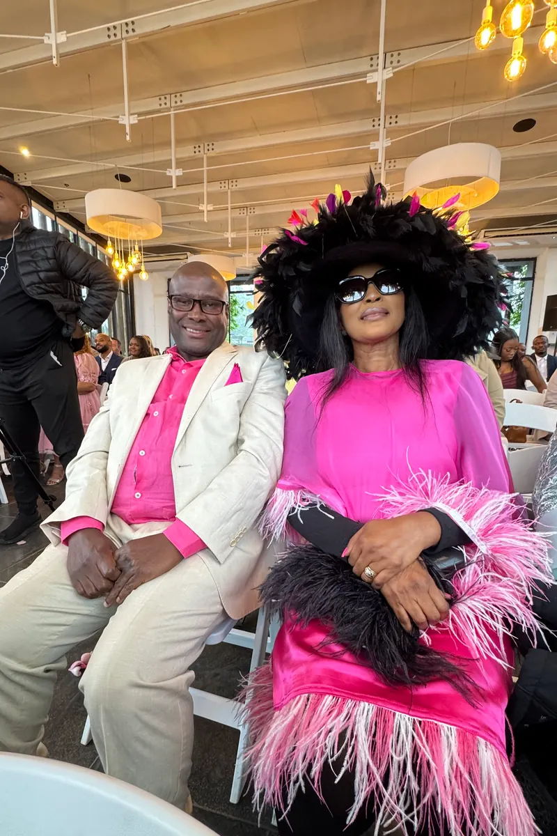 Two wedding guests in pink and cream seated at the ceremony, raw phone photo