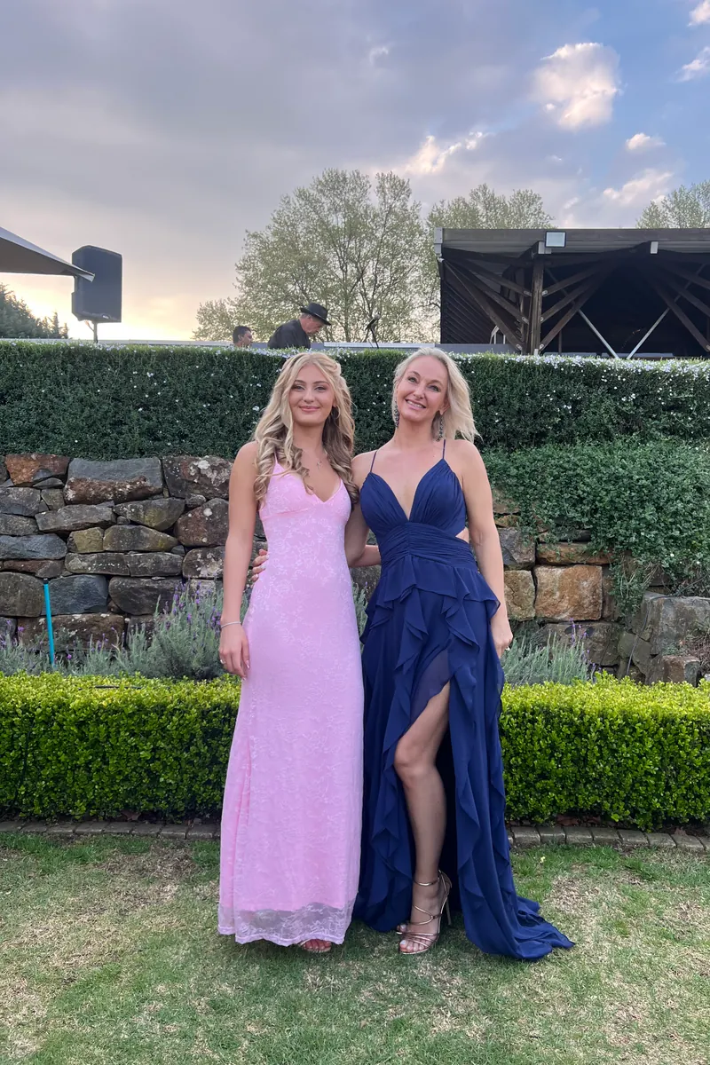 Two bridesmaids in pink and navy gowns in a Midlands wedding garden, raw phone photo