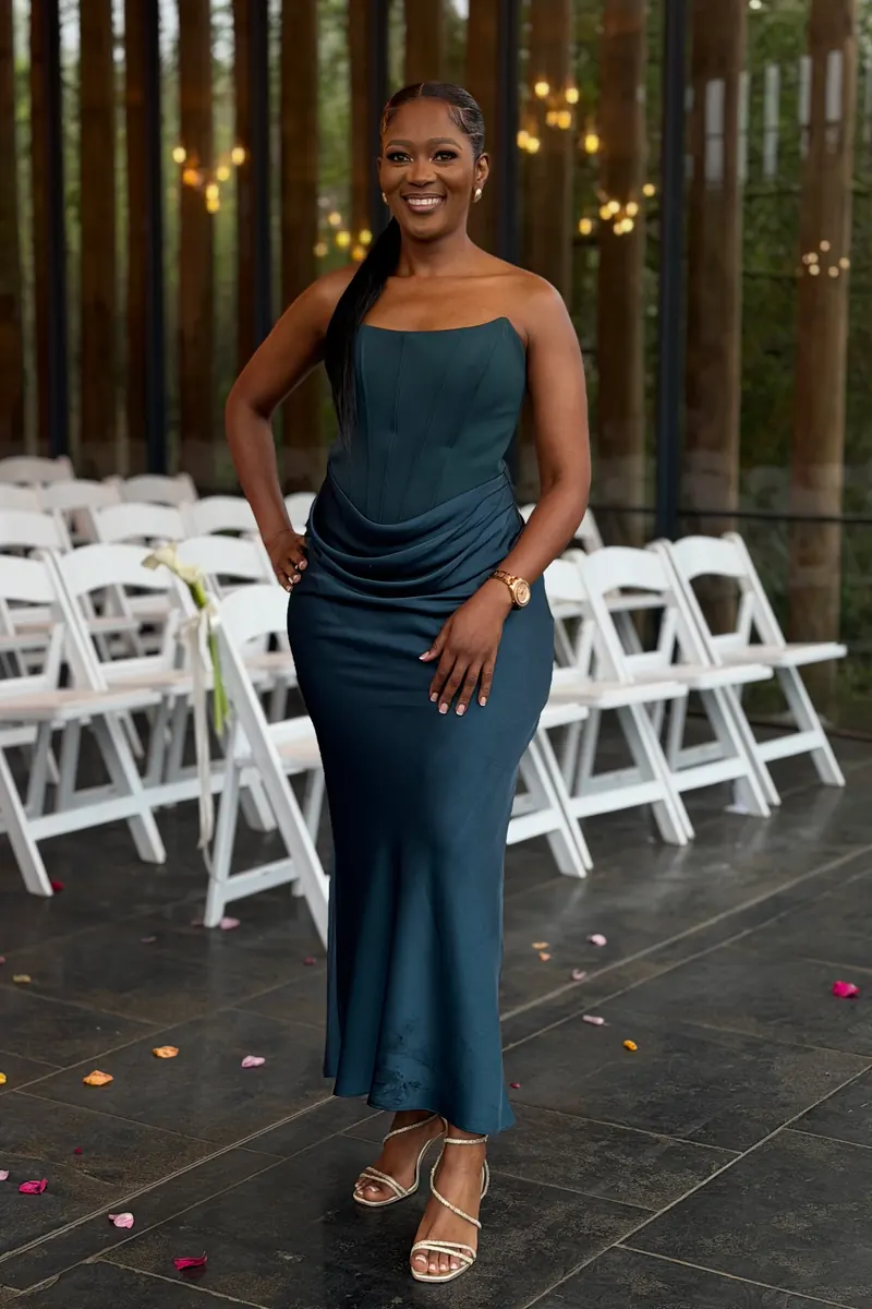 A wedding guest in a teal gown beside the ceremony chairs, raw phone photo