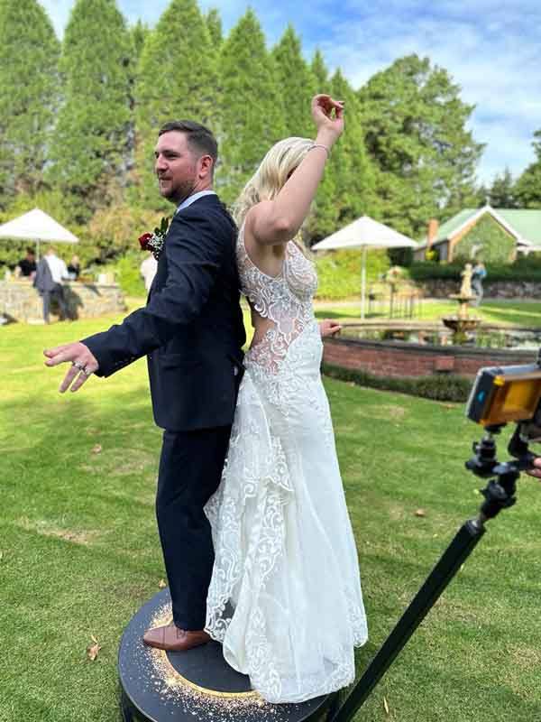 A bride and groom standing on the SPIN360 platform on the lawn at a KZN Midlands wedding venue