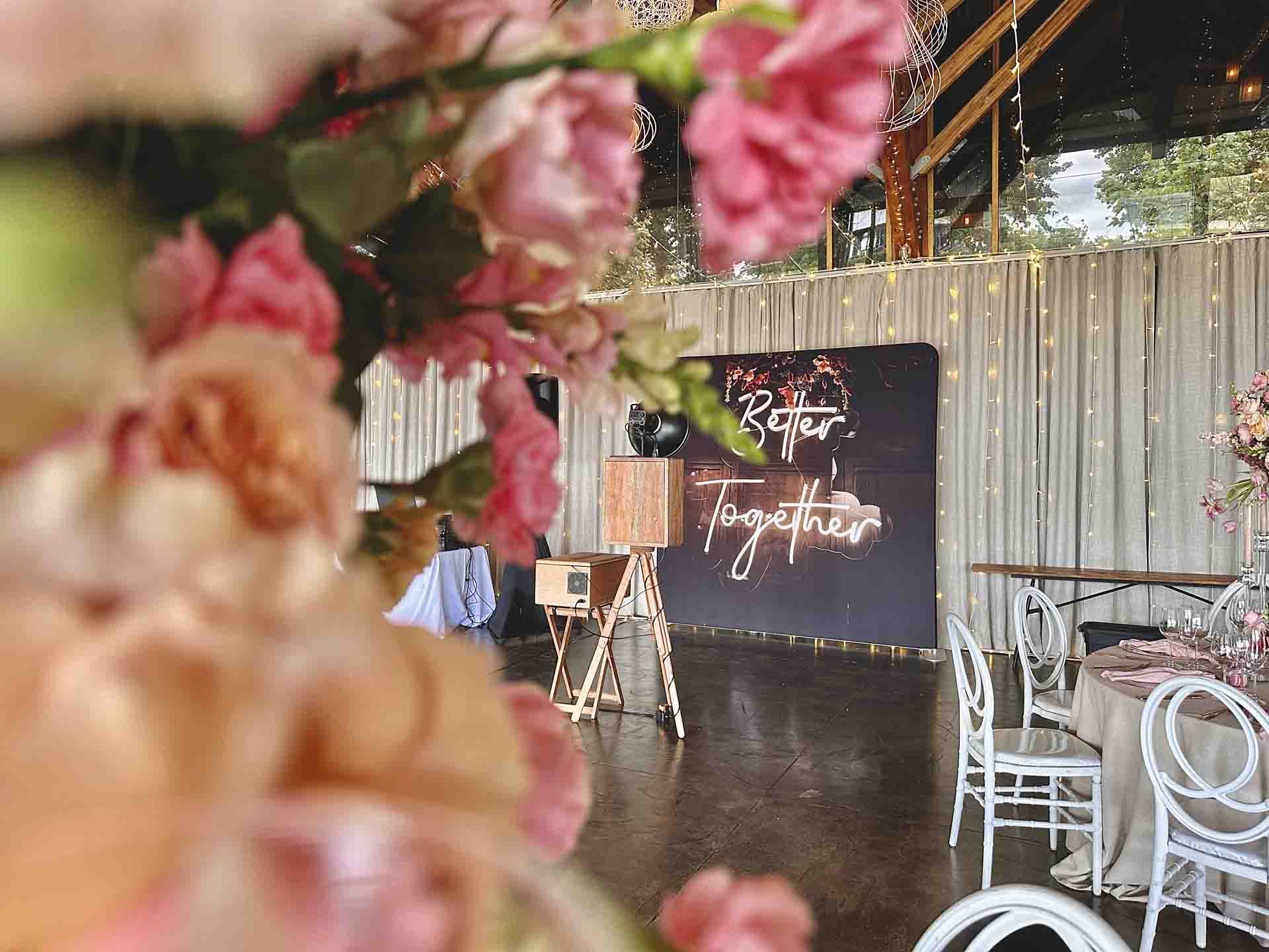The photobooth beside a Better Together neon sign and blossom at a Nottingham Road wedding venue