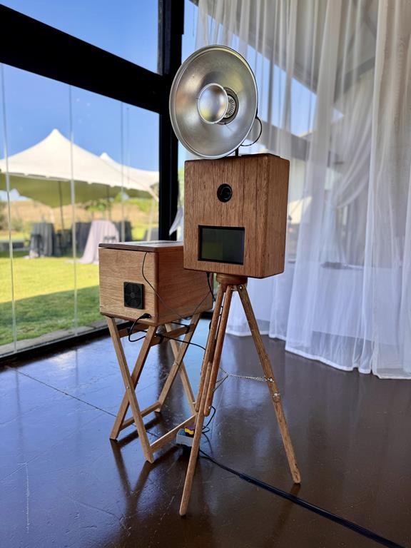 The handcrafted wooden retro photobooth on its tripod with a silver ring flash, set up at a Midlands venue
