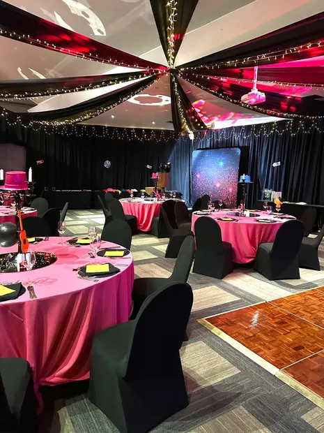 A function room at Alpine Heath set with pink linen and draped ceiling lights before a gala dinner
