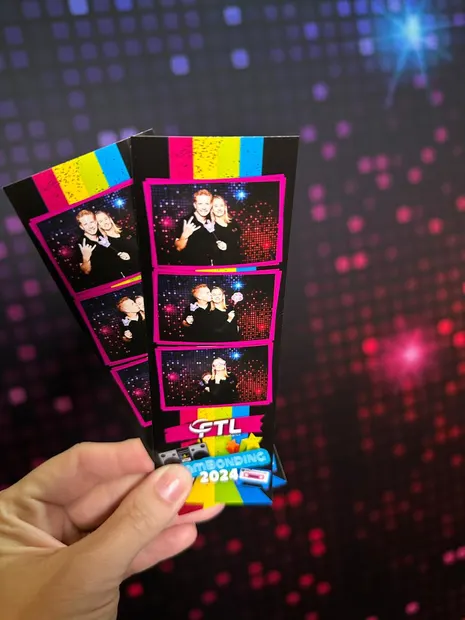 A printed photostrip held up against the disco backdrop at Alpine Heath