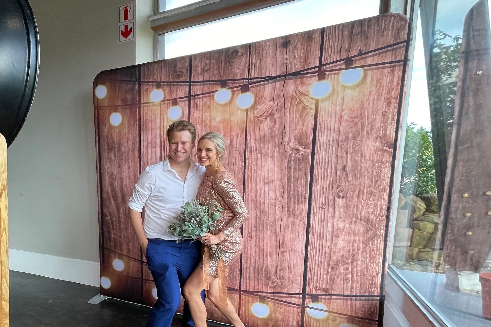 A couple posing against the timber photobooth backdrop at Brahman Hills, Nottingham Road