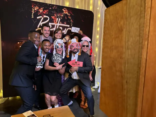 Wedding guests posing with props in front of the photobooth backdrop at Brahman Hills