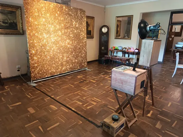 The lit gold sequin backdrop and props table beside the photobooth at Collisheen