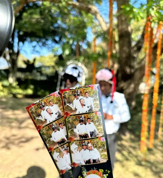 A guest holding two printed photostrips outdoors at a Collisheen wedding