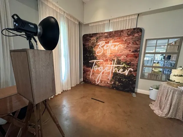 The photobooth beside a Better Together neon backdrop and the cake table at Fordoun