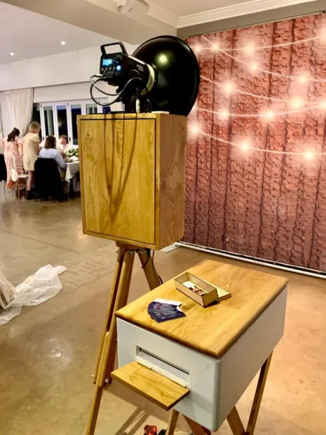The photobooth and a lit brick backdrop with guests seated behind at Fordoun