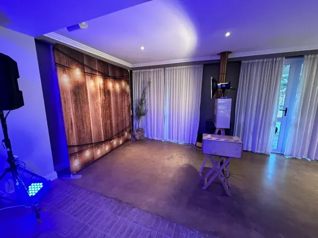 The lit timber backdrop and photobooth in the reception room at Fordoun under blue uplighting