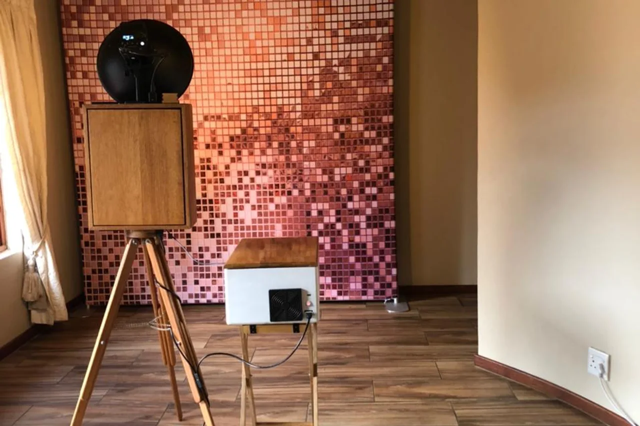 The retro photobooth against a rose-gold backdrop under the thatched roof and chandelier at Granny Mouse Country House