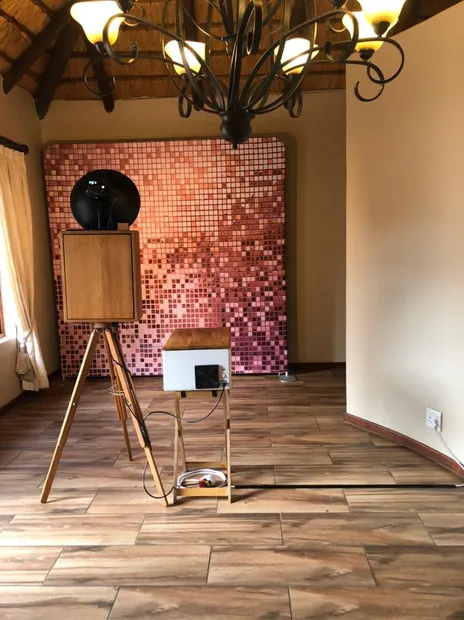 The retro photobooth against a rose-gold backdrop under the thatched roof and chandelier at Granny Mouse
