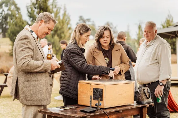 Guests gathered around the instant printing kiosk on the lawn at Haycroft Farm