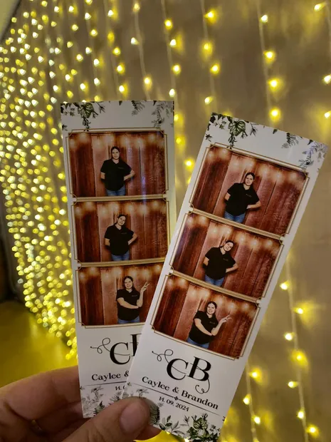 Printed photostrips held up against fairy lights at a Haycroft Farm wedding