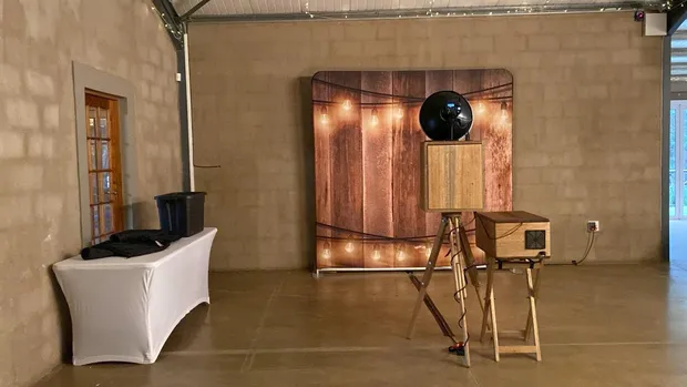 The retro photobooth and a lit timber backdrop set up in the hall at Haycroft Farm