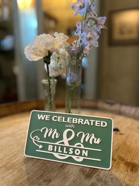 A photobooth sign on a barrel table beside the flowers at a Highgate wedding