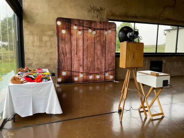 The retro photobooth and a lit timber backdrop beside the props table at Netherwood Farm
