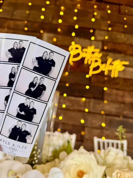 A photostrip held beside a Better Together neon sign at a Netherwood Farm wedding