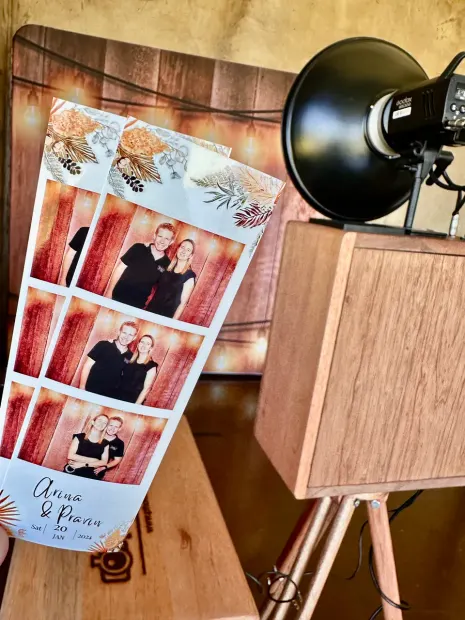 A printed photostrip held up beside the photobooth at Netherwood Farm
