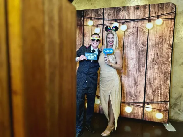A couple posing with props in front of the lit timber backdrop at Netherwood Farm