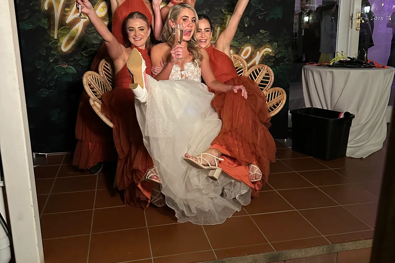 A bride and her bridesmaids posing in front of the Better Together neon backdrop at Providence