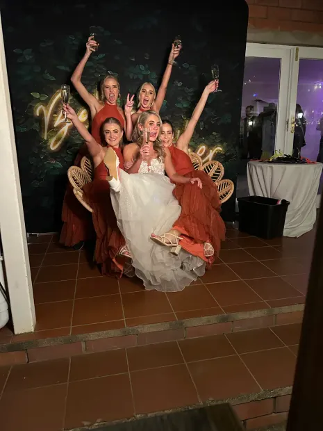 A bride and her bridesmaids posing in front of the Better Together backdrop at Providence
