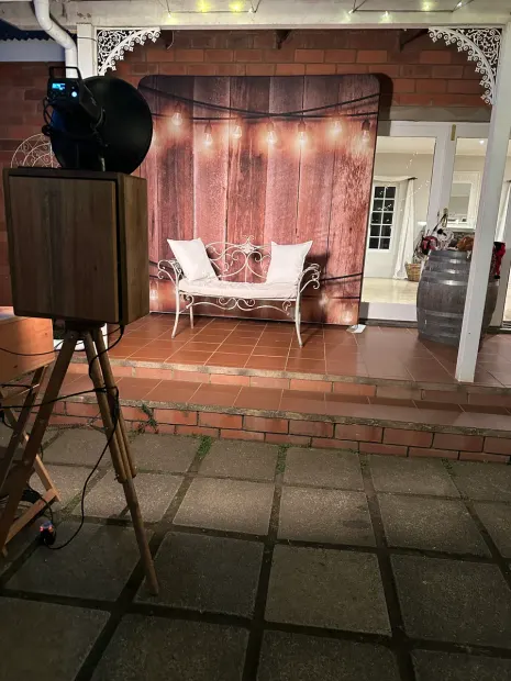 The retro photobooth and lit timber backdrop on the brick veranda at Providence