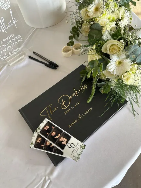 The photobooth guest book and a photostrip beside the flowers at a Sweet Home wedding