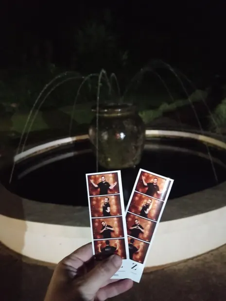 Two printed photostrips held up at the lit water feature at Sweet Home