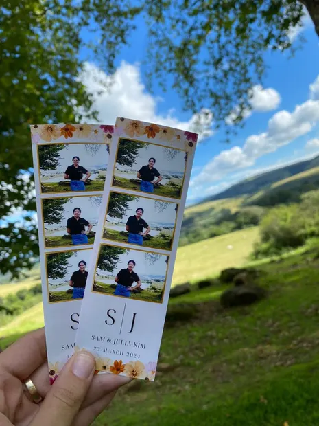 Printed photostrips held up over the green valley at The Glades Farm