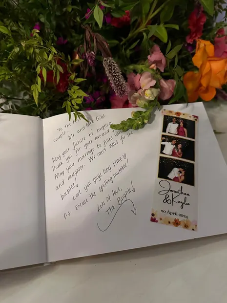 The photobooth guest book open beside the flowers at a wedding at The Groves