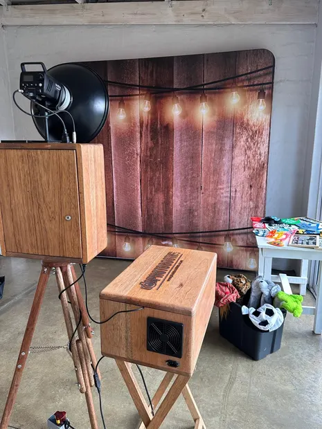 The photobooth and a lit timber backdrop with the props basket alongside at The Groves