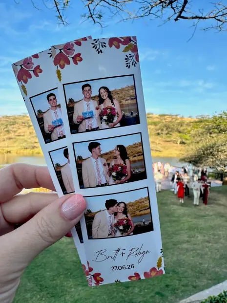 A printed photostrip held up with the ceremony on the lawn behind at Wingrove Valley